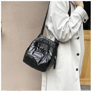 Close-up of black quilted down fabric crossbody bag featuring a fashion logo tag