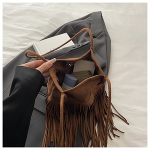 Détail de l'intérieur d'un sac seau à franges en daim marron avec rangement pour accessoires