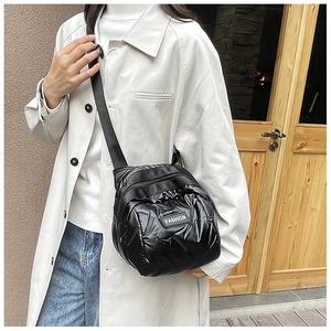 Detail of black glossy puffer crossbody bag featuring a FASHION label and nylon strap