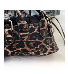 Detail of leopard print handbag featuring drawstring closure and embossed fashion text