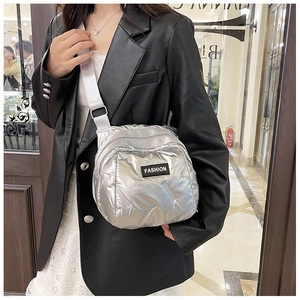Close-up of silver quilted crossbody bag with FASHION patch on a street style model
