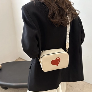 Minimalist beige crossbody bag with red heart pattern and patterned shoulder strap