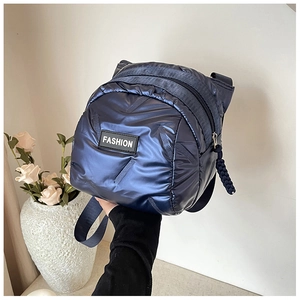 Detail of the navy blue puffer bag featuring shiny quilted fabric and a fashion label