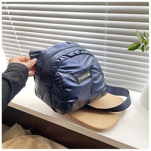 Close-up of quilted navy blue puffer bag with FASHION label and zip closure