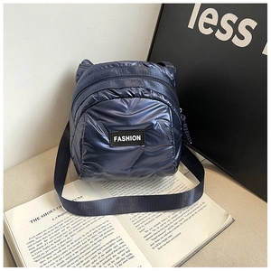 Detail view of navy blue quilted puffer mini bag with Fashion rubber tag on an open book