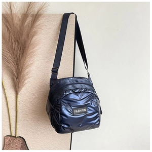 Detail of dark blue quilted puffer bag with FASHION label and adjustable strap