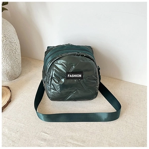 Close-up of dark green quilted mini crossbody bag with double zipper and fashion label