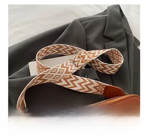Detail of woven geometric wide shoulder strap with gold buckle and leather connectors
