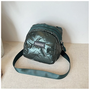 Detailed close-up of dark green quilted puffer crossbody bag with fashion tag and zipper