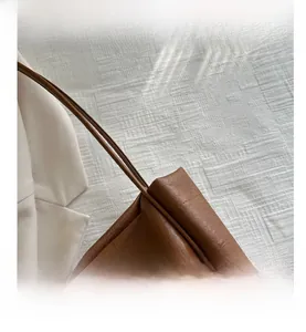 Detail showing the pleated side structure and stitching of the dark brown leather tote bag