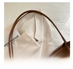 Detailed close-up of brown litchi grain leather tote bag shoulder strap and texture