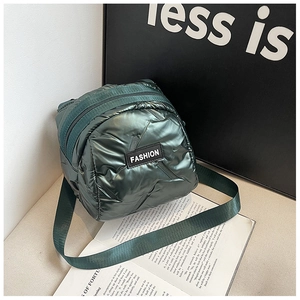 Detail of a dark green quilted mini bag with glossy finish and 'FASHION' label