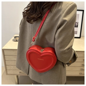 Detailed view of heart-shaped red leather crossbody bag with golden FASHION & BAG lettering