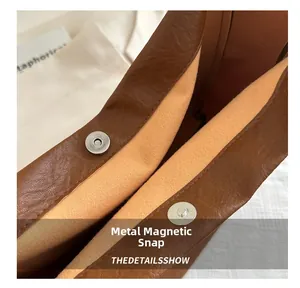Close-up of the metal magnetic snap closure on a pebbled leather caramel tote bag
