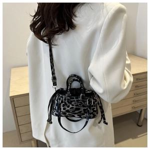 Close-up of leopard print handbag with silver hardware and adjustable strap on a white blazer