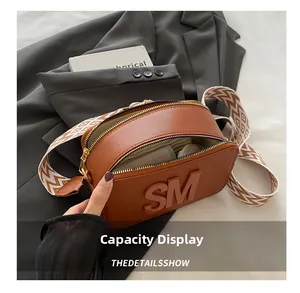 Detail of brown camera bag showing spacious interior with double zipper and logo