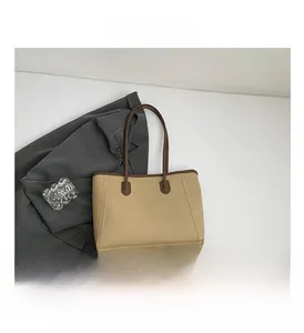 Macro detail of the beige leather tote bag with contrasting dark brown handles and clean trim
