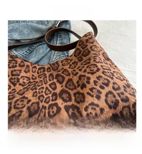 Detail shot of leopard print tote bag with brown leather straps on denim background