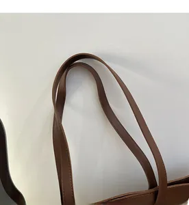 Detailed close-up of comfortable double handles on a premium brown leather tote bag
