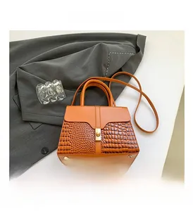 Detailed view of the bright orange bag with crocodile embossed leather and gold lock