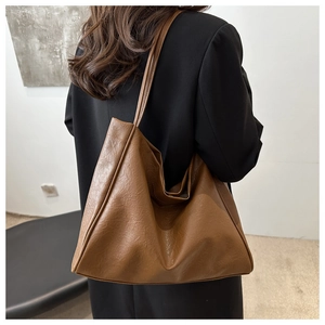 Brown faux leather tote bag with natural texture shown in a casual shoulder carry pose