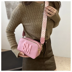Pink camera bag detail with 3D SM letter embossing and geometric wide shoulder strap