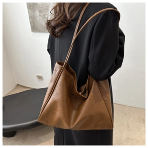 Detail view of large dark brown tote bag worn over the shoulder showing soft leather texture