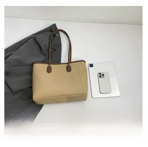 Minimalist khaki tote bag with brown leather trim shown with a tablet and smartphone