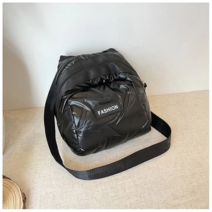 Detailed macro of black quilted down fabric crossbody bag with FASHION woven label