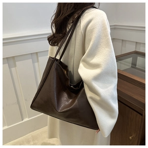 Close-up of a large dark brown tote bag in faux leather with sleek stitching details