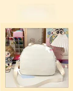 White semi-circular nylon crossbody bag with wide shoulder strap shown on a desk