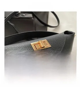 Détail d'un sac à main en cuir noir grainé avec un fermoir rotatif en métal doré