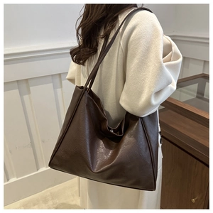 Detail of the dark brown matte leather texture on a large minimalist shoulder tote bag