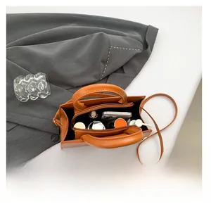 Internal view of the orange leather handbag showing zipper compartment and daily essentials