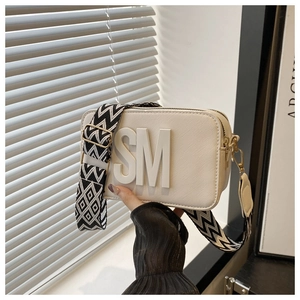 Detailed macro view of white Saffiano leather camera bag with SM logo and wide fabric strap