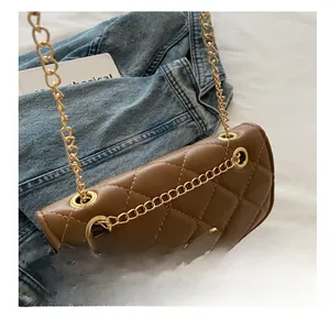 Close-up of brown quilted leather bag with golden chain strap and metal buckle detail