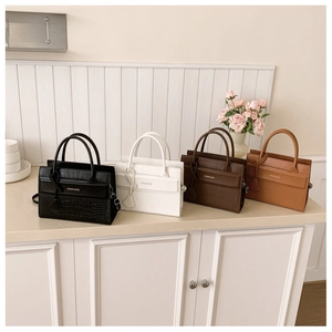 Detail of four chic faux-crocodile leather handbags in neutral tones on a stylish desktop