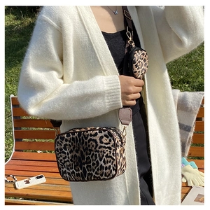 Detail of leopard print crossbody bag and round coin purse shown in a lifestyle scene