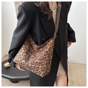 Detail of leopard print hobo bag with adjustable brown leather strap on model shoulder