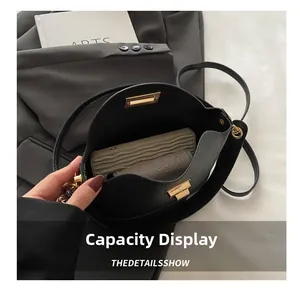 Détail montrant la capacité interne du sac en cuir noir avec boucle métallique dorée