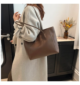 Detail of a large chocolate brown leather tote bag with elegant decorative stitching