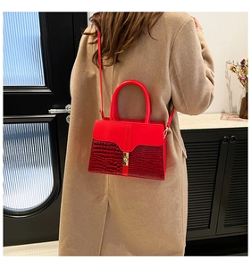 Detailed close-up of a red leather handbag with crocodile pattern and golden metal clasp