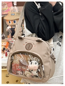 Detail of beige cartoon bear ita bag showing transparent pocket with anime charms