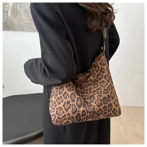 Detailed view of leopard print tote bag with brown straps worn on a black blazer
