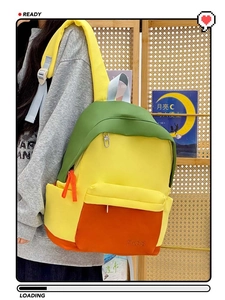 Close-up of tricolor patchwork backpack with TASS logo and front zipper pocket