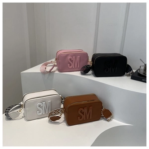 Detail view of four colorful camera bags with wide jacquard straps and SM lettering decoration