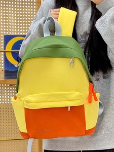 Detail view of the tricolor canvas backpack with green, yellow, and orange color blocking