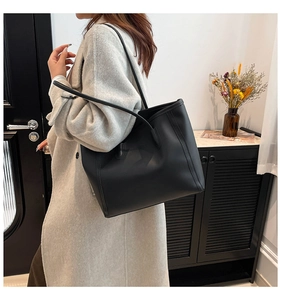 Close-up of a black matte leather tote bag carried on a shoulder for daily commuting