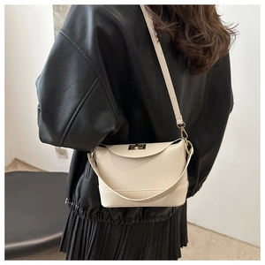 Détail du sac seau en cuir crème avec fermoir rotatif en métal doré et texture grainée