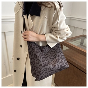 Close-up of leopard print hobo bag with brown leather strap styled with a beige coat